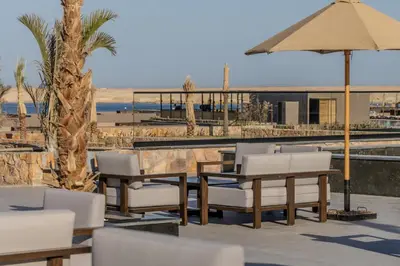 a table and chairs and an umbrella at a beach at Aldiana Club Naga Bay in Hurghada