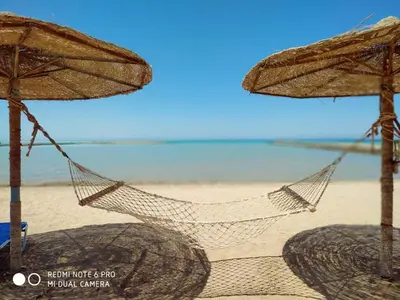 a hammock on a beach with two umbrellas at Tertels beach resort F 1-7 in Hurghada