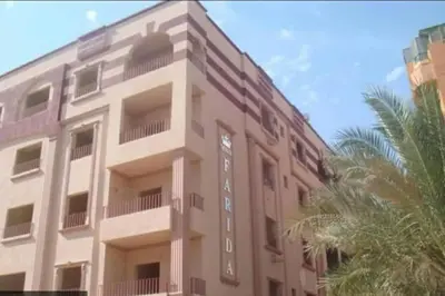 a pink building with a palm tree in front of it at Farida in Hurghada