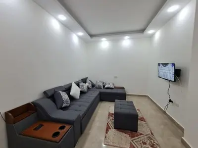 a living room with a blue couch and a tv at Golden Home in Hurghada