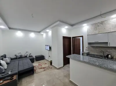 a living room with a black couch and a kitchen at Golden Home in Hurghada