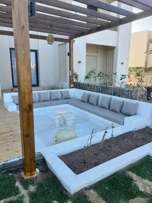 a large white couch sitting under a pergola at Stylish 1BR Ground With Free Pool & Lagoon Access In Gouna in Hurghada