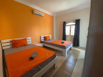 two beds in a room with orange walls at Hurghada - Magawish Villa 3 in Hurghada