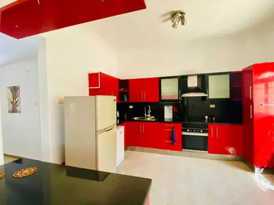 a kitchen with red cabinets and a white refrigerator at Hurghada - Magawish Villa 3 in Hurghada