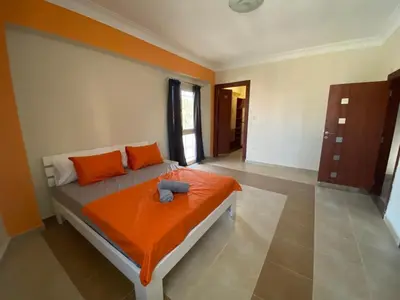 a bedroom with a bed with an orange blanket at Hurghada - Magawish Villa 3 in Hurghada