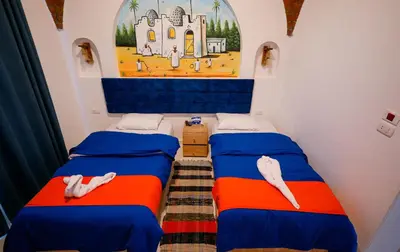 two beds in a room with a painting on the wall at JAREEDY Guest house in Shellal