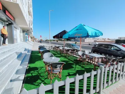 a row of tables and chairs with an umbrella on a sidewalk at Hotel apartment with a private beach in Hurghada