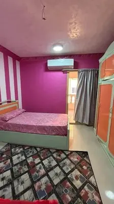 a room with two beds and a purple wall at The best view of the Nile in Naj‘ al ‘Amrāb