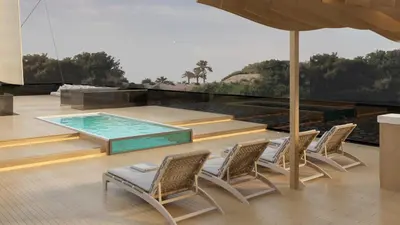 a patio with a pool and chairs and an umbrella at Nefertem Yacht, All-Inclusive Boutique Charter in Luxor