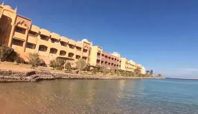 a row of buildings on a beach next to the water at Tiba Golden Resort in Hurghada