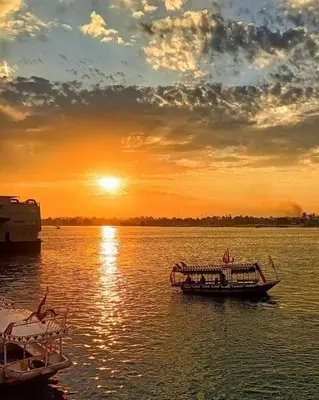 a boat in the water with the sunset in the background at البيت النوبى in Aswan