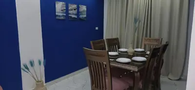 a dining room table with chairs and a blue wall at Red Sea Hurghada Summer in Winter in Hurghada