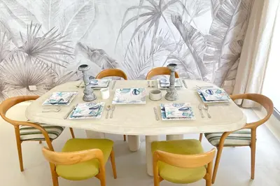 a dining room table with chairs and a table and a wall at Lofty & Lavish 3 BDR Swan Lake El Gouna in Hurghada