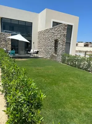 a house with a lawn with a table and an umbrella at Beachfront Spacious Somabay Loft in Hurghada