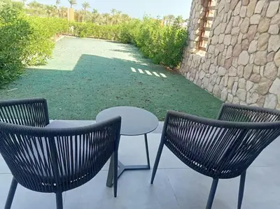 a patio with two chairs and a table and a stone wall at Somabay Seaview 1BR Loft 2 Mins to Beach & Pool in Hurghada