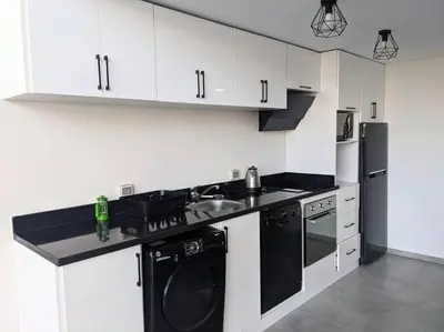 a kitchen with white cabinets and a black dishwasher at Somabay Seaview 1BR Loft 2 Mins to Beach & Pool in Hurghada