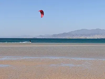a person is flying a kite on the beach at Magical Cabana Steps From Beach & Pool in Hurghada