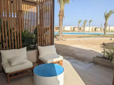 a patio with two chairs and a table and a pool at Magical Cabana Steps From Beach & Pool in Hurghada