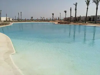 a large pool of blue water with palm trees at Somabay 2BR Grand Cabana Minutes From Pool & Sea in Hurghada
