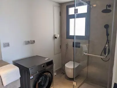 a bathroom with a toilet and a shower with a washing machine at Somabay 2BR Grand Cabana Minutes From Pool & Sea in Hurghada
