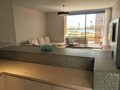 a kitchen with a counter top and a living room at Somabay 2BR Grand Cabana Minutes From Pool & Sea in Hurghada