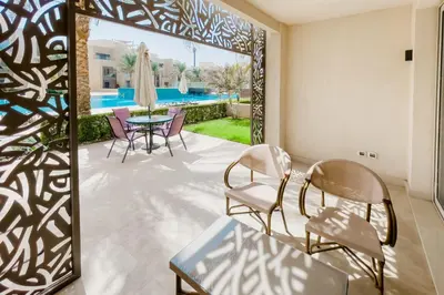 a room with a patio with chairs and a table at Scenic Pool Front 1 BDR Mangroovy Free Pool & Beach in Hurghada