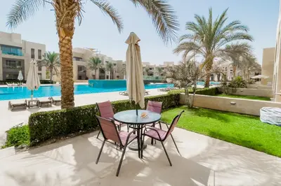 a patio with a table and chairs and a pool at Scenic Pool Front 1 BDR Mangroovy Free Pool & Beach in Hurghada
