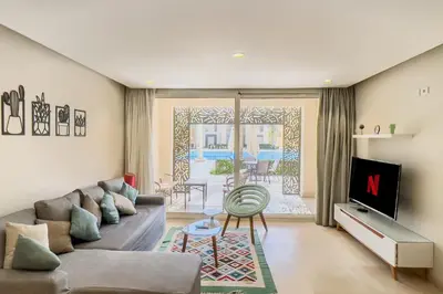 a living room with a couch and a tv at Scenic Pool Front 1 BDR Mangroovy Free Pool & Beach in Hurghada