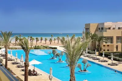a view of a swimming pool with palm trees and the beach at Embellished 2BDR Penthouse Mangroovy Free Pool & Beach in Hurghada