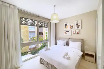 a bedroom with a white bed and a large window at Peaceful & Placid 1 BDR Mangroovy Free Pool & Beach in Hurghada