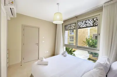 a bedroom with a white bed and a large window at Peaceful & Placid 1 BDR Mangroovy Free Pool & Beach in Hurghada