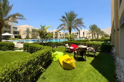 a patio with chairs and a table in the grass at Staggering & Soothing 2 BDR w Pool View Free Pool & Beach Access in Hurghada