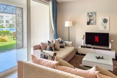 a living room with a couch and a tv at Staggering & Soothing 2 BDR w Pool View Free Pool & Beach Access in Hurghada