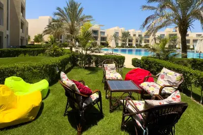 a group of chairs and a table next to a pool at Staggering & Soothing 2 BDR w Pool View Free Pool & Beach Access in Hurghada