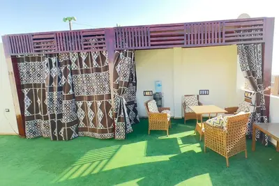 a room with curtains and chairs and a table at Appartement avec rooftop au cœur de Louxor vue sur le Nil in Jazīrat al ‘Awwāmīyah