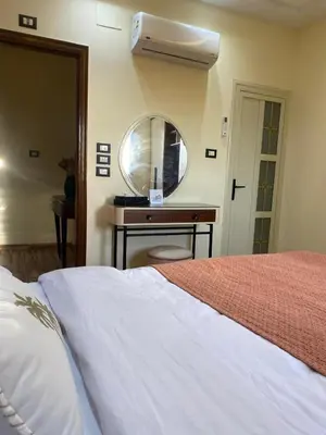 a bedroom with a bed and a mirror and a table at Appartement avec rooftop au cœur de Louxor vue sur le Nil in Jazīrat al ‘Awwāmīyah