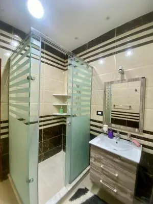 a bathroom with a glass shower and a sink at Appartement avec rooftop au cœur de Louxor vue sur le Nil in Jazīrat al ‘Awwāmīyah