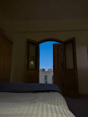a bedroom with a bed and an open window at Pharaohs Apartments in Luxor