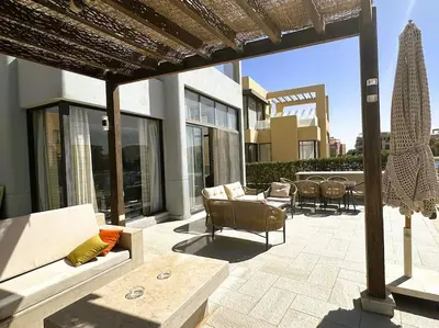 a patio with couches and chairs on a building at Luminous 4BR Villa, Free Pool & Lagoon Access At Gouna in Hurghada