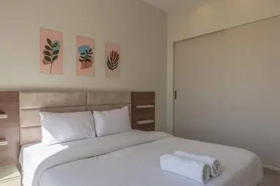 a bedroom with a white bed with three paintings on the wall at Comfy 2BR in Shedwan El Gouna Garden BBQ, Pool, Lagoon in Hurghada