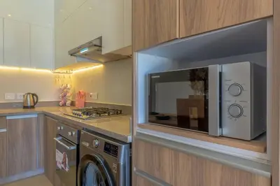 a kitchen with a microwave and a washer and dryer at Comfy 2BR in Shedwan El Gouna Garden BBQ, Pool, Lagoon in Hurghada