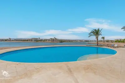 a swimming pool in a resort with a palm tree at Comfy 2BR in Shedwan El Gouna Garden BBQ, Pool, Lagoon in Hurghada