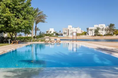 a large blue swimming pool with trees and buildings at Beautiful apartment with roof terrace in Joubal in Hurghada