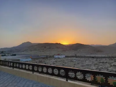 a sunset over a desert with mountains in the background at Carter Guesthouse Luxor 2 in ‘Ezbet Abu Ḥabashi