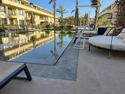a pool at a resort with chairs and a table at Studio El Gouna G Cribs Hotel in Hurghada