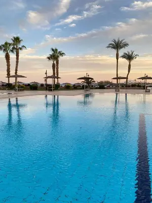 a large swimming pool with palm trees and umbrellas at Esplanada hotel Apartments in Hurghada