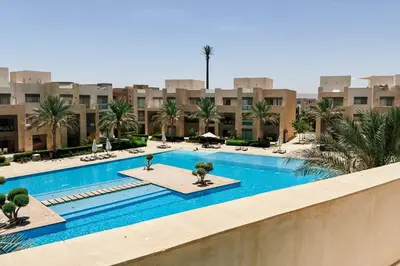 a pool with palm trees and buildings in the background at Stellar 1BDR Mangroovy Free Pool & Beach Access in Hurghada