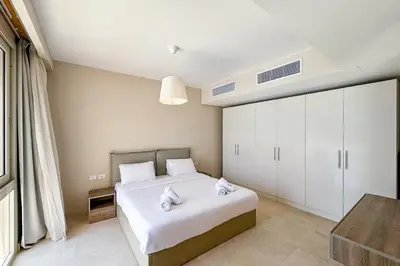 a bedroom with a large white bed and a table at Stellar 1BDR Mangroovy Free Pool & Beach Access in Hurghada