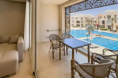 a living room with a table and chairs and a pool at Soothing & Stilly 2BDR Mangroovy Pool & Beach Access in Hurghada
