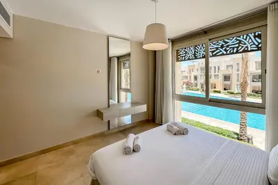 a bedroom with a bed and a large window at Soothing & Stilly 2BDR Mangroovy Pool & Beach Access in Hurghada